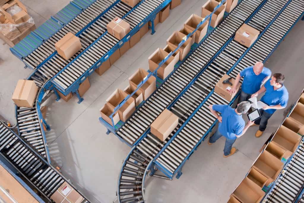 Overhead shot of three men talking in a warehouse about Selling a Business for Retirement in California